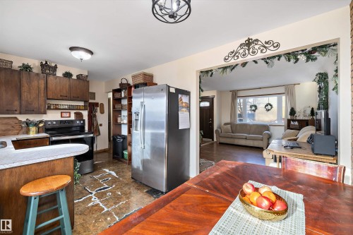 Kitchen featuring stainless steel fridge, range with electric cooktop, light countertops, dark wood finish cabinets, and open floor plan - 5703 143 Avenue, Edmonton, AB - Indoor