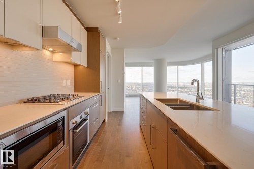 Kitchen featuring extractor fan, modern cabinets, stainless steel appliances, light wood-style floors, and light stone countertops - 3901 10360 102 Street, Edmonton, AB - Indoor Photo Showing Kitchen With Double Sink With Upgraded Kitchen