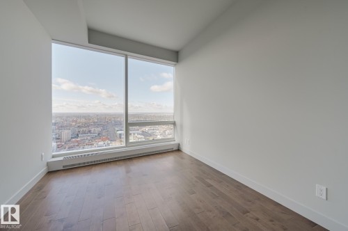 Empty room with wood finished floors and baseboard heating - 3901 10360 102 Street, Edmonton, AB - Indoor Photo Showing Other Room