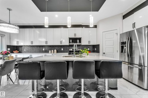 Kitchen with stainless steel appliances, hanging light fixtures, light marble finish floors, and a breakfast bar - 1522 17 Avenue, Edmonton, AB - Indoor Photo Showing Kitchen With Upgraded Kitchen