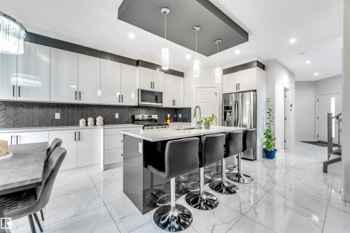 Kitchen featuring a kitchen breakfast bar, modern cabinets, stainless steel appliances, and pendant lighting - 1522 17 Avenue, Edmonton, AB - Indoor Photo Showing Kitchen With Upgraded Kitchen