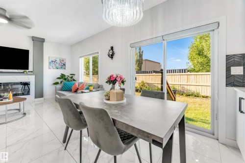 Dining area with hanging lights, a glass covered fireplace, a ceiling fan, and light marble finish flooring - 1522 17 Avenue, Edmonton, AB - Indoor Photo Showing Dining Room With Fireplace