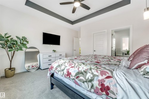 Bedroom featuring a raised ceiling, light carpet, a ceiling fan, and ensuite bathroom - 1522 17 Avenue, Edmonton, AB - Indoor Photo Showing Bedroom