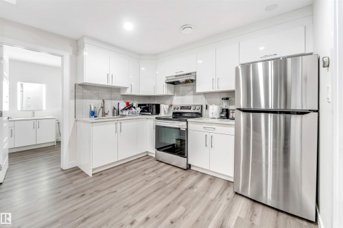 Kitchen featuring stainless steel appliances, white cabinetry, light wood-type flooring, light countertops, and recessed lighting - 1522 17 Avenue, Edmonton, AB - Indoor Photo Showing Kitchen
