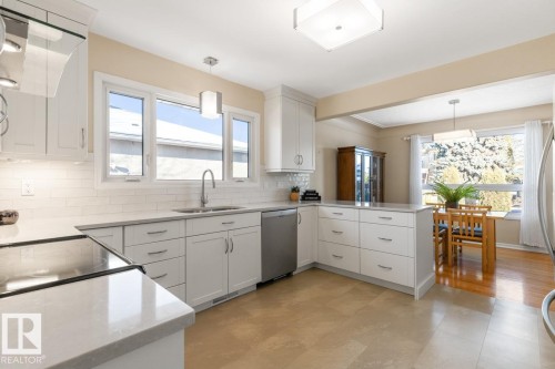White kitchen with quartz counters and stainless steel appliances - 8707 Strathearn Drive, Edmonton, AB - Indoor Photo Showing Kitchen With Upgraded Kitchen