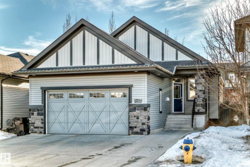 View of front of home with stone siding, board and batten siding, driveway, and a garage - 7719 Getty Wynd, Edmonton, AB - Outdoor