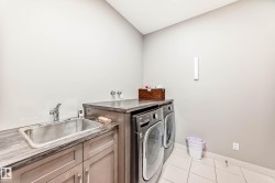 Laundry room featuring light tile patterned floors, washing machine and dryer, and cabinet space - 