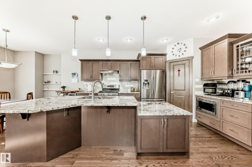 Kitchen with light stone counters, stainless steel appliances, and decorative light fixtures - 7719 Getty Wynd, Edmonton, AB - Indoor Photo Showing Kitchen With Double Sink With Upgraded Kitchen