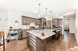 Kitchen with light stone counters, an island with sink, pendant lighting, beverage cooler, and light wood finished floors - 