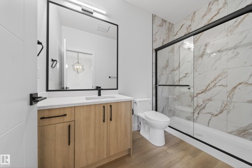 Full bathroom featuring a marble finish shower, vanity, and light wood-style floors - 436 Crystal Creek Link, Leduc, AB - Indoor Photo Showing Bathroom