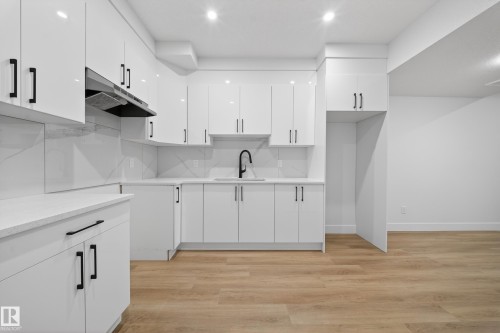Kitchen with white cabinetry, light wood finished floors, modern cabinets, light stone counters, and backsplash - 436 Crystal Creek Link, Leduc, AB - Indoor Photo Showing Kitchen