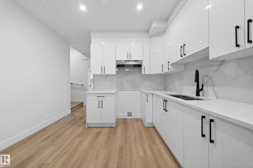 Kitchen with white cabinets, light wood-style floors, light stone counters, modern cabinets, and backsplash - 436 Crystal Creek Link, Leduc, AB - Indoor Photo Showing Kitchen With Double Sink With Upgraded Kitchen
