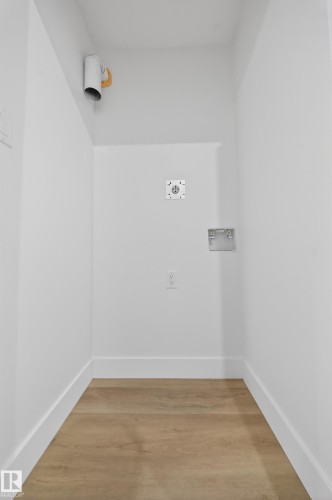 Laundry area with light wood-style floors and washer hookup - 436 Crystal Creek Link, Leduc, AB - Indoor