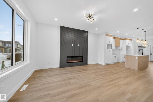 Unfurnished living room featuring suspended lighting, light wood finished floors, and a large fireplace - 436 Crystal Creek Link, Leduc, AB - Indoor With Fireplace
