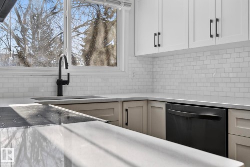 Kitchen featuring dishwasher, light stone counters, white cabinets, and decorative backsplash - 9969 171 Ave, Edmonton, AB - Indoor Photo Showing Kitchen