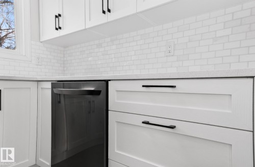 Kitchen view of light stone countertops, white cabinets, and stainless steel dishwasher - 9969 171 Ave, Edmonton, AB - Indoor