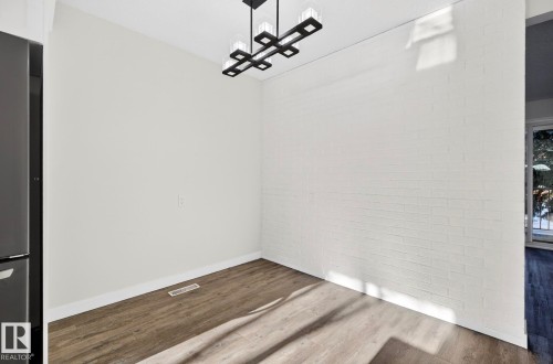 Unfurnished dining area with brick wall and wood finished floors - 9969 171 Ave, Edmonton, AB - Indoor Photo Showing Other Room