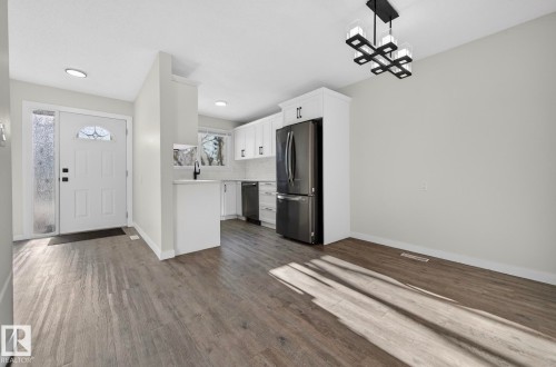 Kitchen with white cabinetry, light countertops, stainless steel appliances, dark wood-style flooring, and a chandelier - 9969 171 Ave, Edmonton, AB - Indoor Photo Showing Kitchen