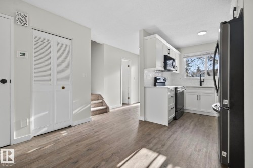 Kitchen with freestanding refrigerator, white cabinetry, range with electric stovetop, and light countertops - 9969 171 Ave, Edmonton, AB - Indoor Photo Showing Kitchen