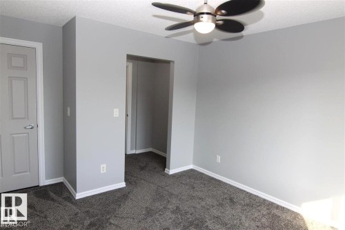 Unfurnished bedroom featuring dark colored carpet, a textured ceiling, ceiling fan, and a closet - 404 4407 23 Street, Edmonton, AB - Indoor