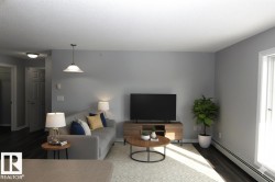Living room with a baseboard heating unit, wood finished floors, and a textured ceiling - 