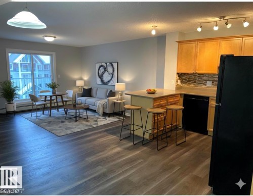 Kitchen with black appliances, open floor plan, decorative backsplash, a peninsula, and a kitchen breakfast bar - 404 4407 23 Street, Edmonton, AB - Indoor