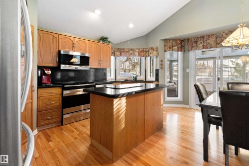 Kitchen with stainless steel appliances, dark countertops, vaulted ceiling, a kitchen island, and light wood-style flooring - 519 Buchanan Road, Edmonton, AB - Indoor Photo Showing Kitchen