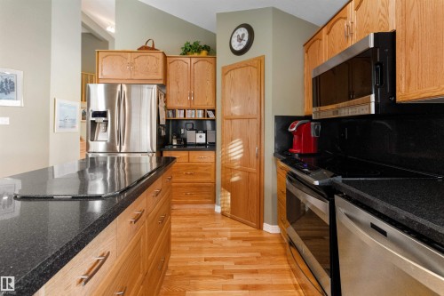 Kitchen featuring stainless steel appliances, backsplash, dark stone countertops, light wood-type flooring, and lofted ceiling - 519 Buchanan Road, Edmonton, AB - Indoor Photo Showing Kitchen