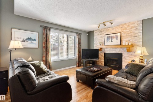 Living room with light wood finished floors, rail lighting, a fireplace, and a textured ceiling - 519 Buchanan Road, Edmonton, AB - Indoor Photo Showing Living Room With Fireplace