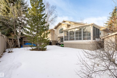 Snow covered back of property featuring a sunroom, a fenced backyard, and stucco siding - 519 Buchanan Road, Edmonton, AB - Outdoor