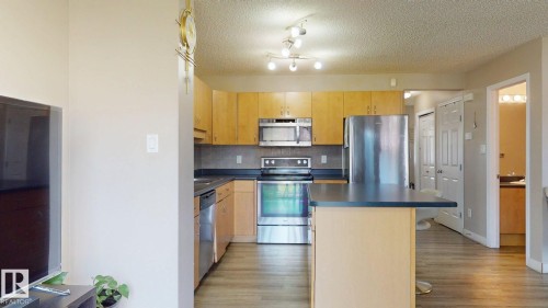 Kitchen featuring stainless steel appliances, a kitchen island, tasteful backsplash, dark countertops, and a breakfast bar - 1150 37B Avenue, Edmonton, AB - Indoor Photo Showing Kitchen With Stainless Steel Kitchen