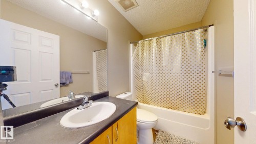 Full bath featuring vanity, a textured ceiling, and shower / tub combo with curtain - 1150 37B Avenue, Edmonton, AB - Indoor Photo Showing Bathroom