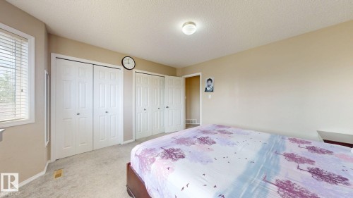 Carpeted bedroom featuring two closets and a textured ceiling - 1150 37B Avenue, Edmonton, AB - Indoor Photo Showing Bedroom
