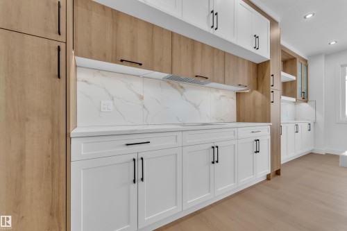 Dual tone kitchen featuring dual tone cabinets, recessed lighting, light wood-style floors, and decorative backsplash - 202 Basin Court, Leduc, AB - Indoor