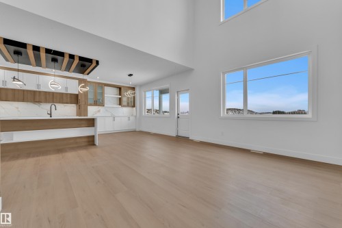 Unfurnished living room featuring light wood-style floors and a high ceiling - 202 Basin Court, Leduc, AB - Indoor Photo Showing Other Room