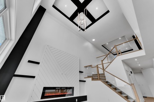 Staircase featuring recessed lighting, a glass covered fireplace, and a high ceiling - 202 Basin Court, Leduc, AB - Indoor Photo Showing Other Room With Fireplace