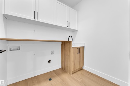 Laundry room with light wood-style flooring and cabinet space - 202 Basin Court, Leduc, AB - Indoor Photo Showing Other Room
