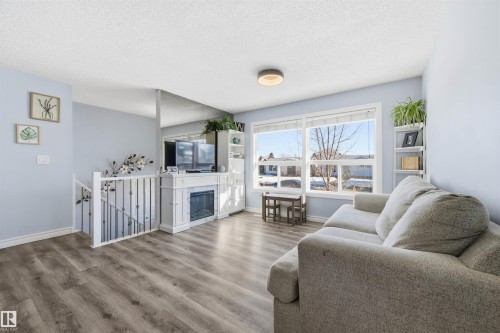 Living area with a textured ceiling, wood finished floors, and a glass covered fireplace - 848 Millbourne Road E, Edmonton, AB - Indoor Photo Showing Living Room With Fireplace