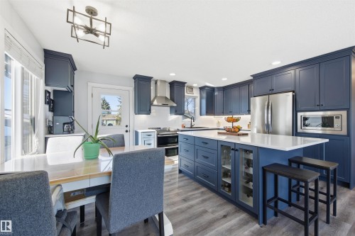 Kitchen featuring blue cabinetry, a breakfast bar area, stainless steel appliances, light wood-type flooring, and recessed lighting - 848 Millbourne Road E, Edmonton, AB - Indoor