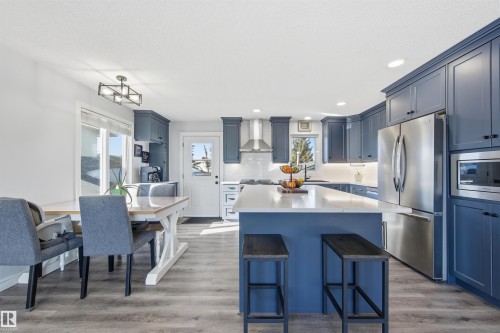 Kitchen with blue cabinetry, stainless steel appliances, a center island, recessed lighting, and a kitchen bar - 848 Millbourne Road E, Edmonton, AB - Indoor Photo Showing Other Room