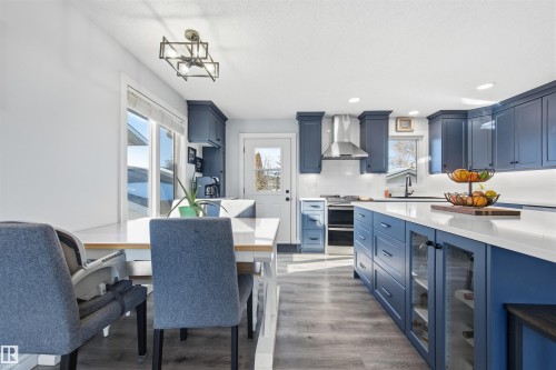 Kitchen featuring blue cabinetry, beverage cooler, light wood finished floors, double oven range, and light stone countertops - 848 Millbourne Road E, Edmonton, AB - Indoor