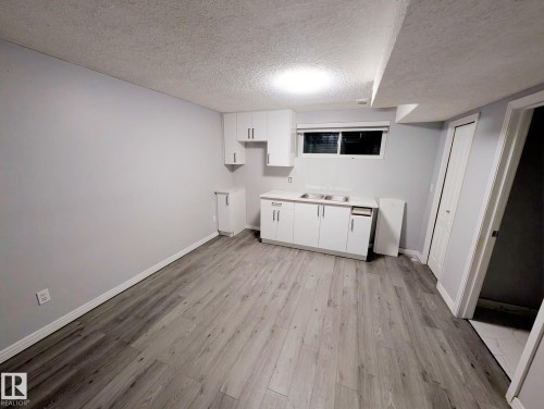 Kitchen featuring white cabinets, light countertops, a textured ceiling, and light wood-style flooring - 315 Wild Rose Way, Edmonton, AB - Indoor