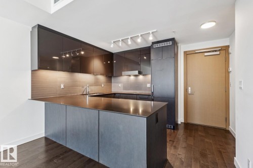 Kitchen featuring a peninsula, dark countertops, modern cabinets, dark wood-type flooring, and tasteful backsplash - 3104 10360 102 Street, Edmonton, AB - Indoor Photo Showing Kitchen