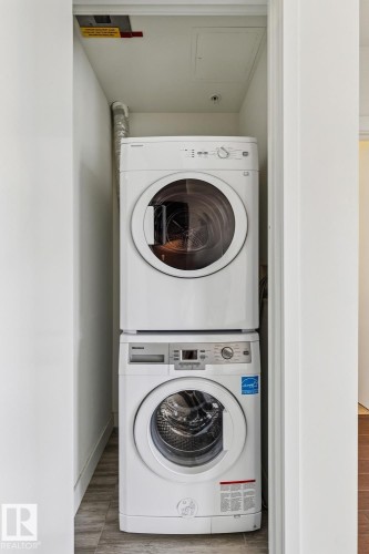 Laundry area with stacked washing machine and dryer and wood finished floors - 3104 10360 102 Street, Edmonton, AB - Indoor Photo Showing Laundry Room