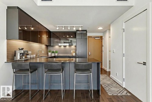 Kitchen with a peninsula, modern cabinets, a kitchen bar, dark wood-type flooring, and backsplash - 3104 10360 102 Street, Edmonton, AB - Indoor Photo Showing Kitchen With Upgraded Kitchen
