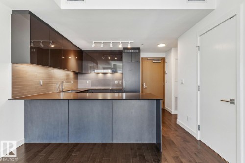 Kitchen with a peninsula, modern cabinets, dark countertops, track lighting, and built in fridge - 3104 10360 102 Street, Edmonton, AB - Indoor