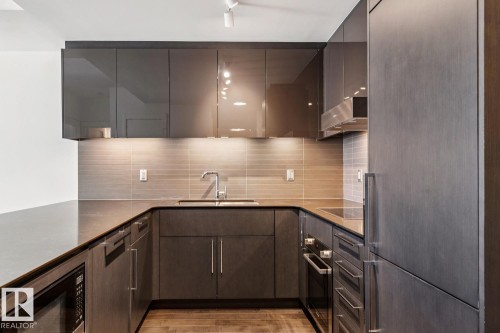 Kitchen with black appliances, backsplash, dark wood finish cabinets, light wood-style floors, and modern cabinets - 3104 10360 102 Street, Edmonton, AB - Indoor Photo Showing Kitchen With Upgraded Kitchen