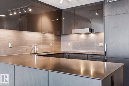 Kitchen featuring track lighting, modern cabinets, dark stone counters, backsplash, and ventilation hood - 3104 10360 102 Street, Edmonton, AB - Indoor Photo Showing Kitchen With Upgraded Kitchen