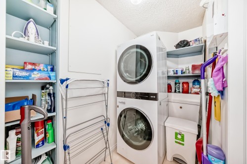 Laundry room with stacked washer / drying machine and a textured ceiling - 108 12028 103 Avenue, Edmonton, AB - Indoor Photo Showing Laundry Room