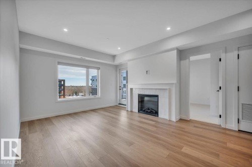WITH ELECTRIC FIREPLACE, VINYL PLANK FLOORING AND PARTIAL RAVINE VIEWS - 322 7459 May Common Nw, Edmonton, AB - Indoor Photo Showing Living Room With Fireplace
